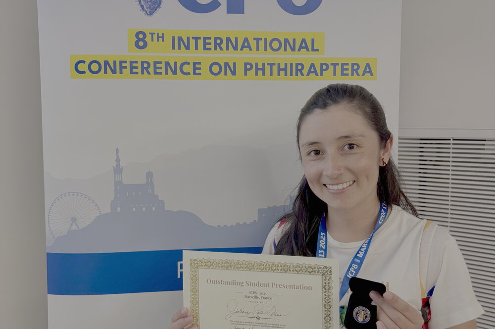 A photo of a student holding her award in front of a poster