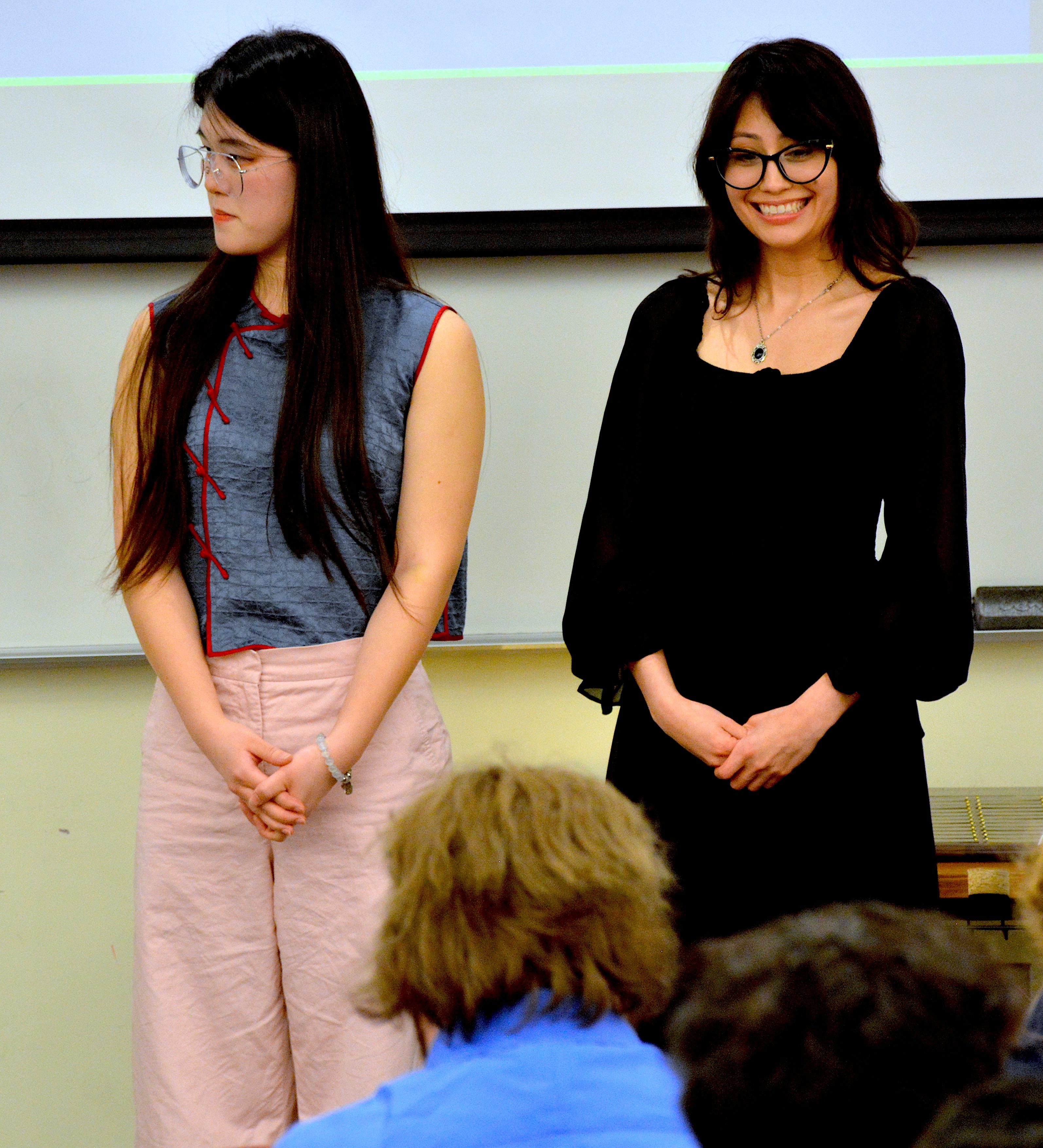 A student smiling at someone in the crowd while another one is looking off to the left
