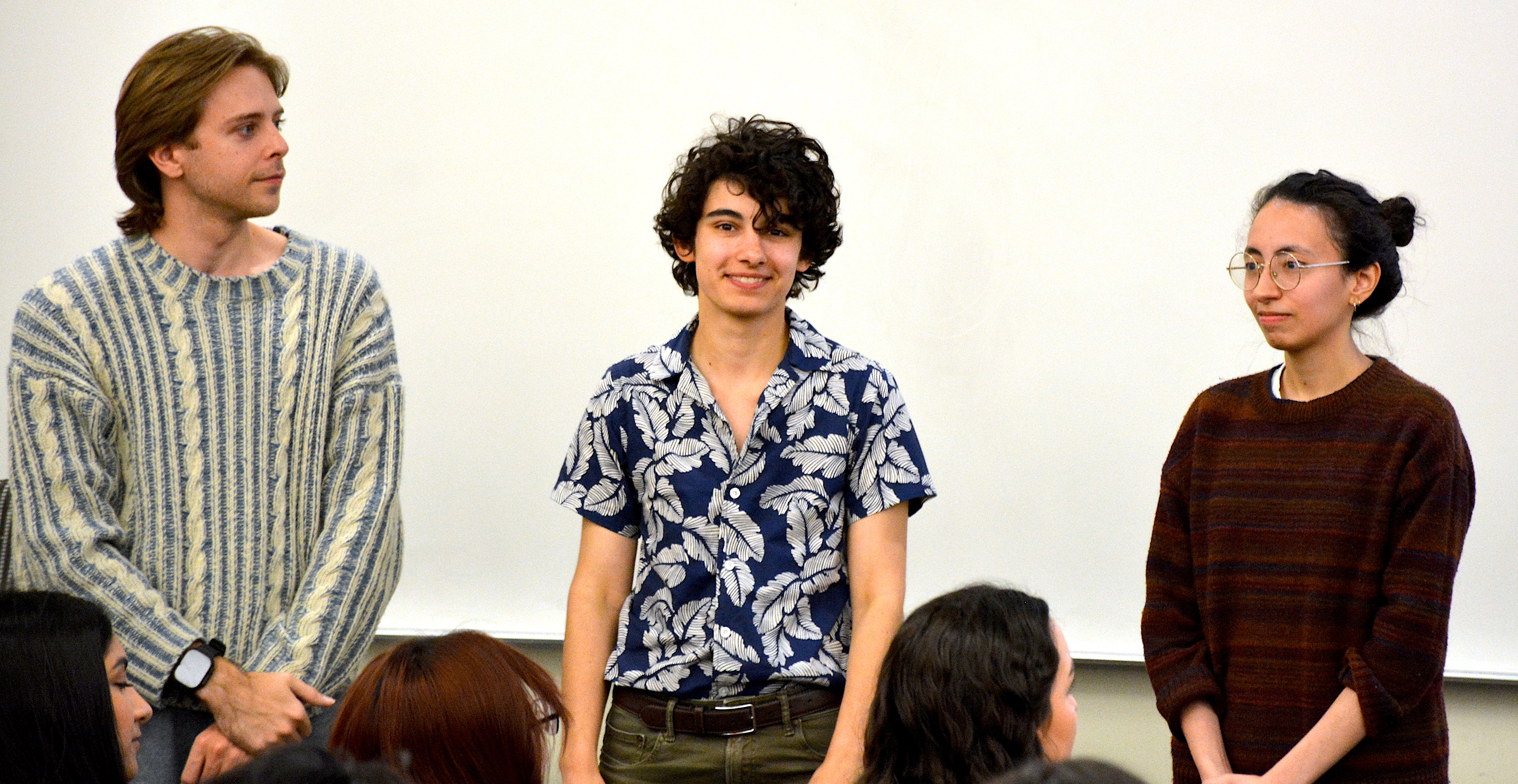 Three students, one looking left, one right, and one smiling straight ahead
