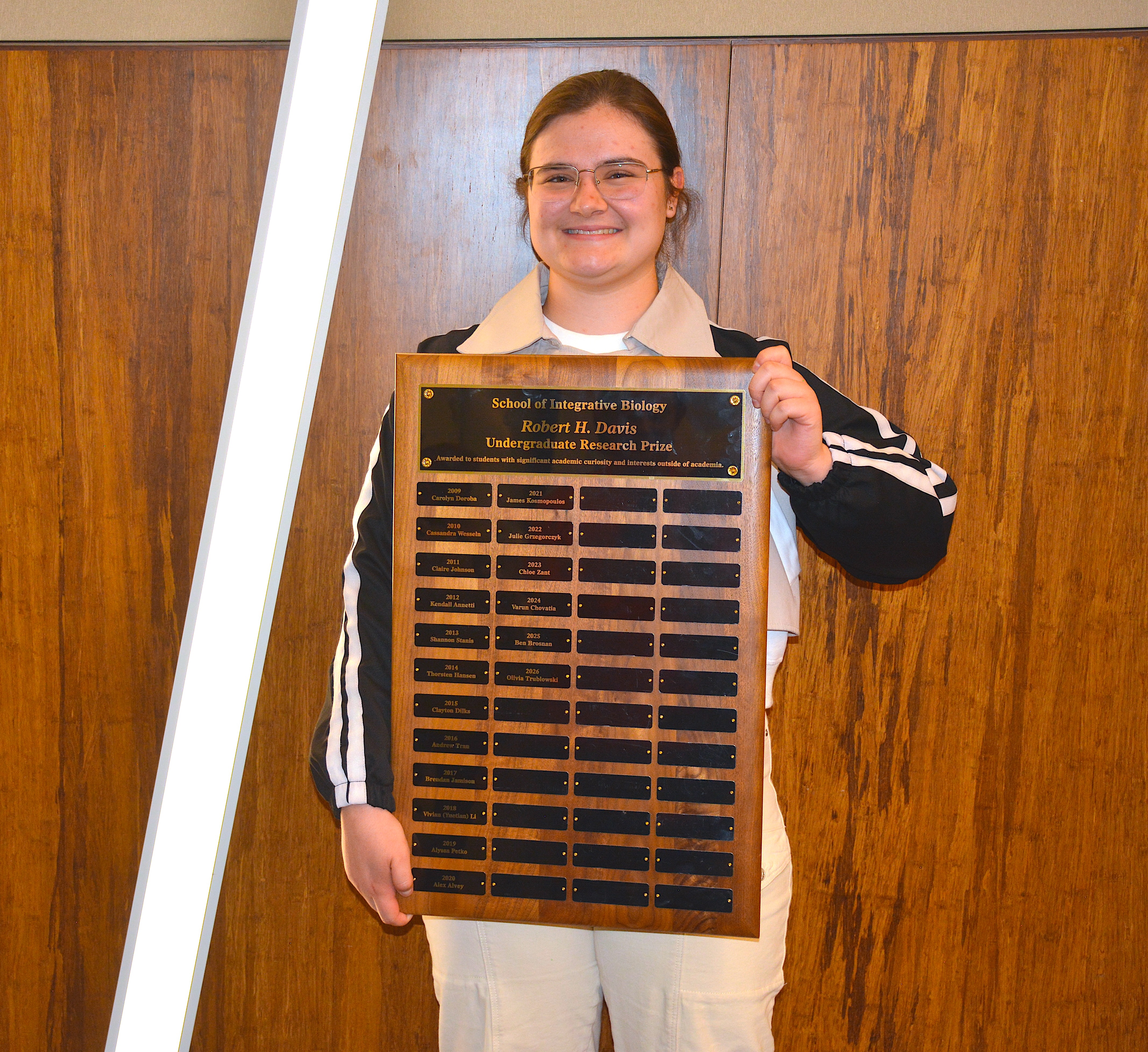 A student smiling and holding a plaque