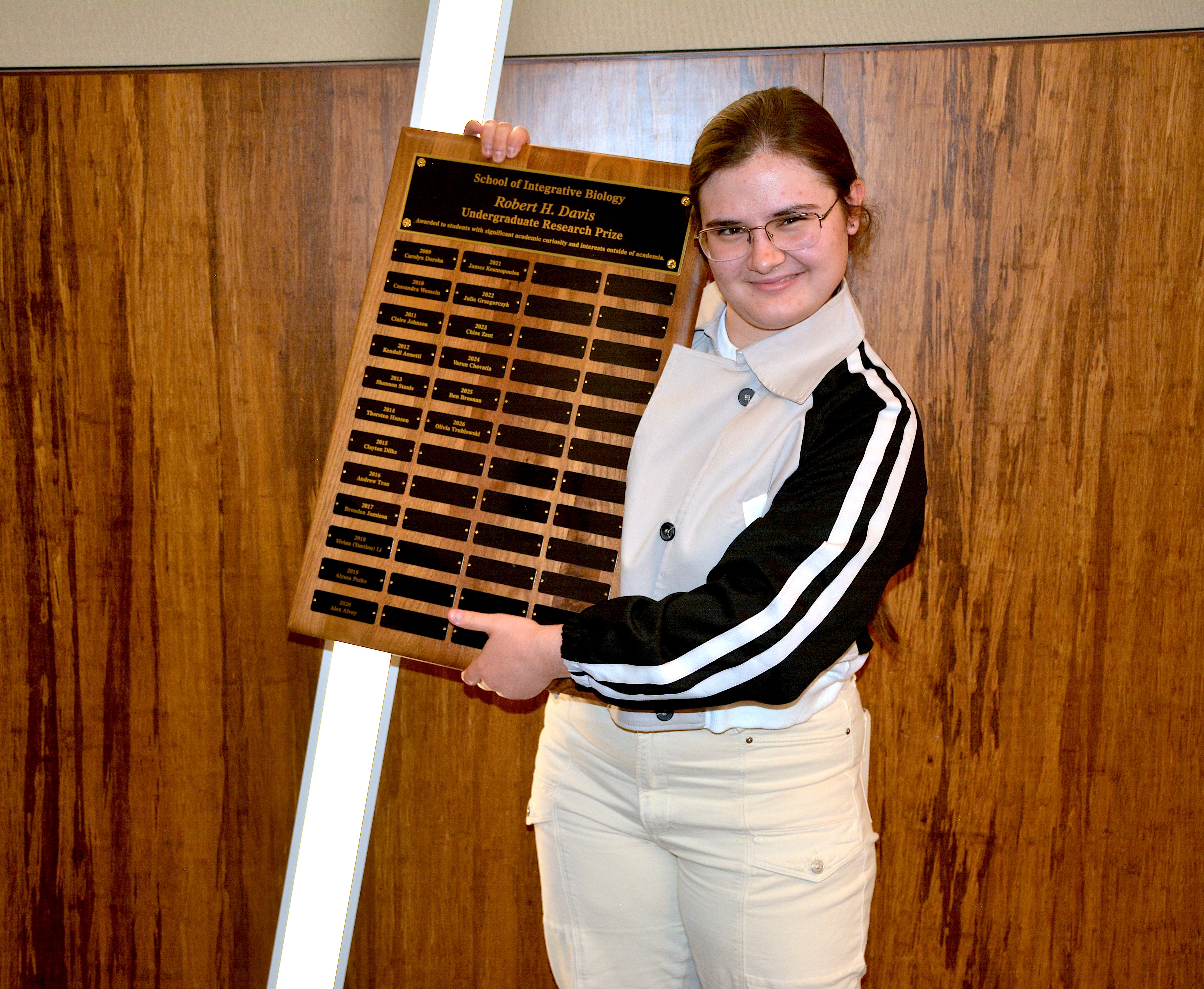 A student doing a goofy pose with a plaque