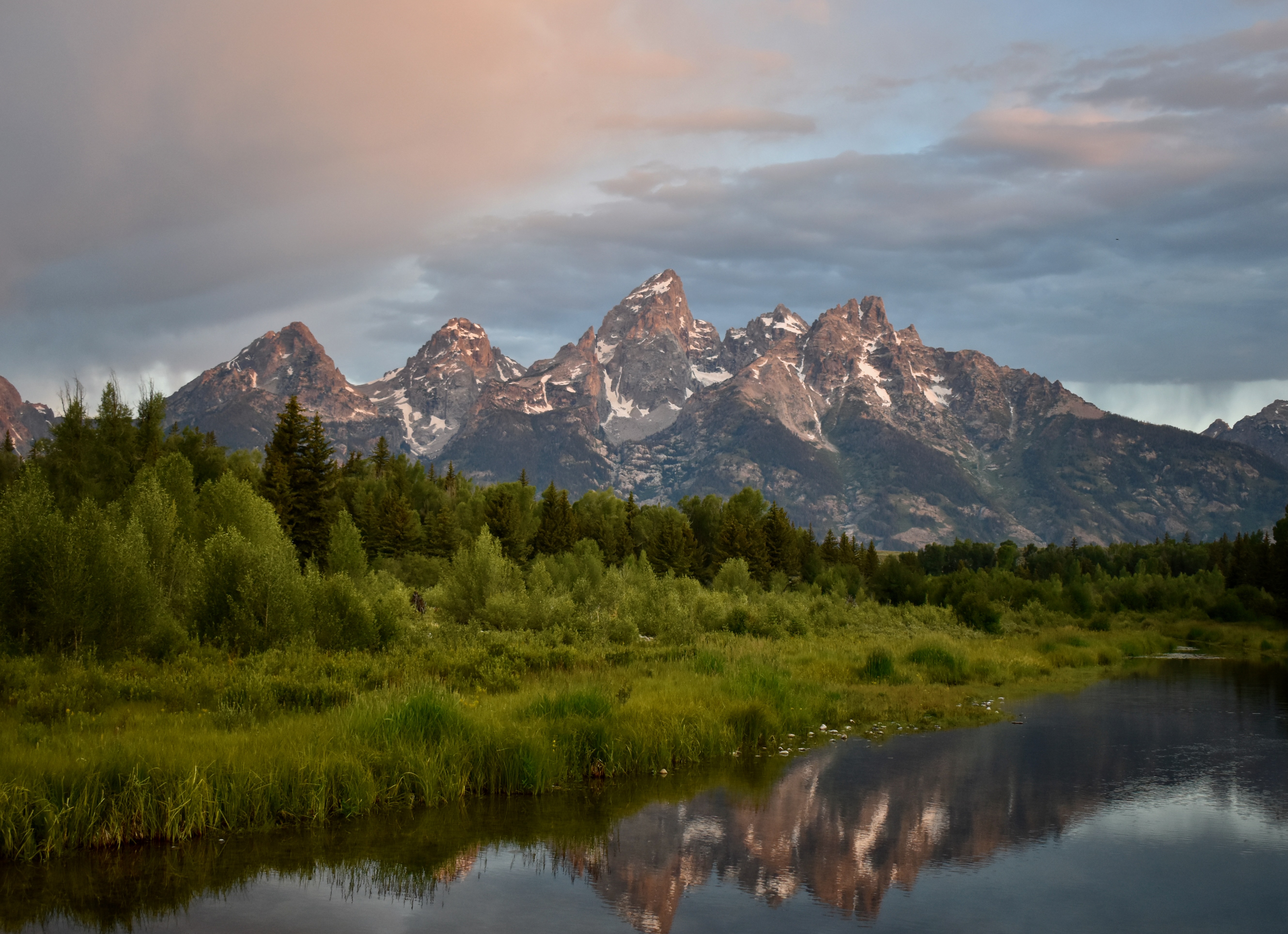 Mountains reflecting in water with a bunch of greenery in front of them