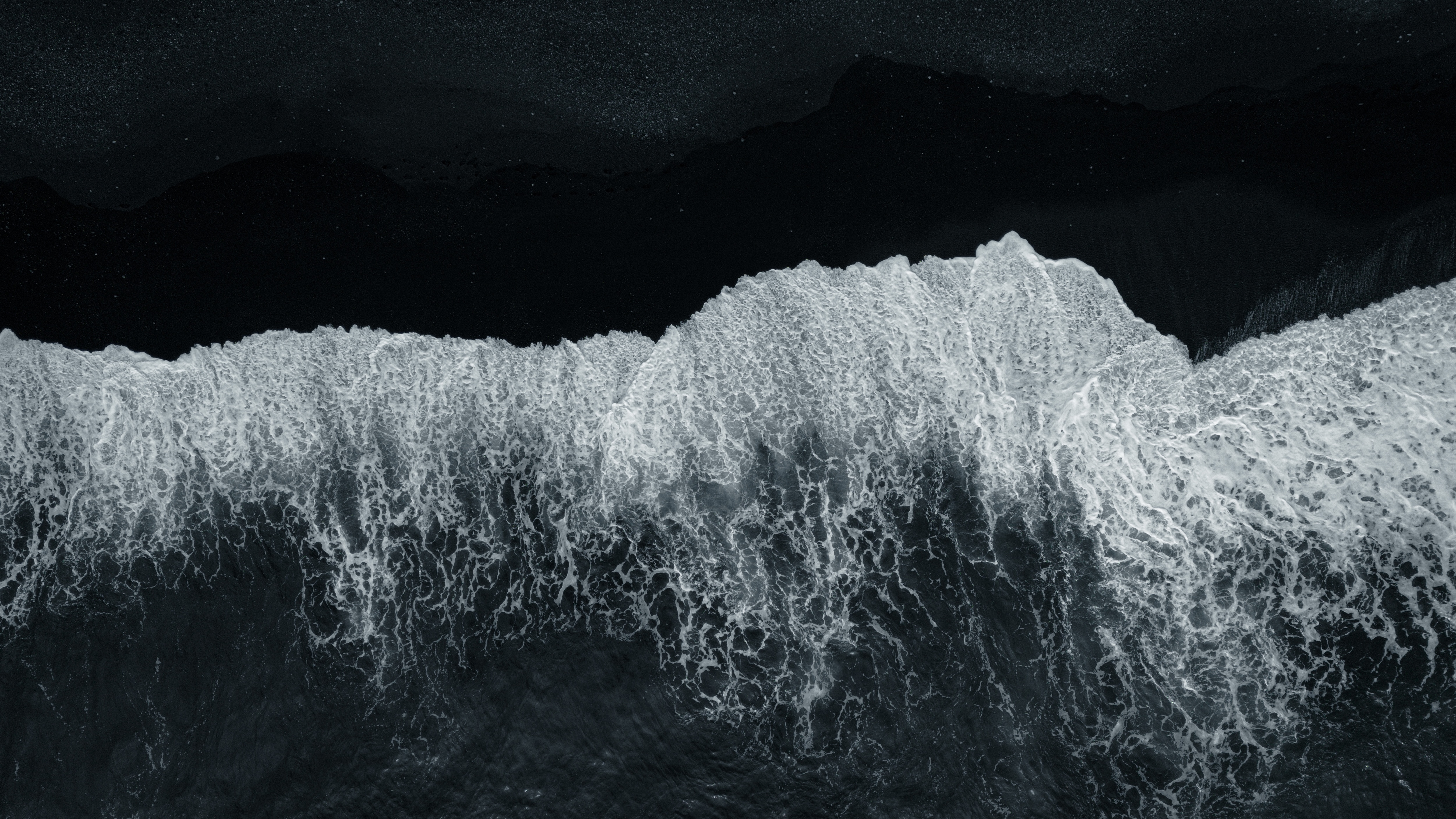 Ocean waves crashing against a black background