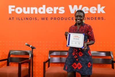A woman smiling and holding an award in front of an orange background