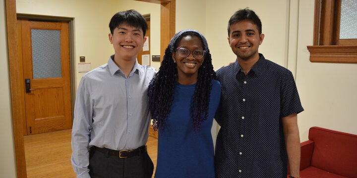 a photo of three students smiling with their arms around each other