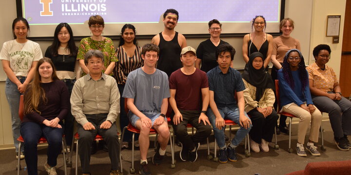 A group of students sitting and standing in front a display