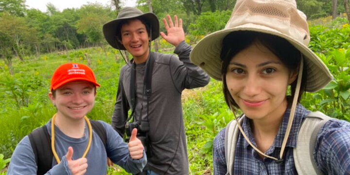 Three students standing outside and smiling at the camera