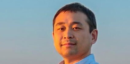 headshot of a man in a blue collared shirt