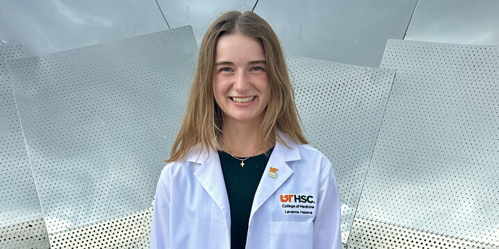 A student standing in a white lab coat