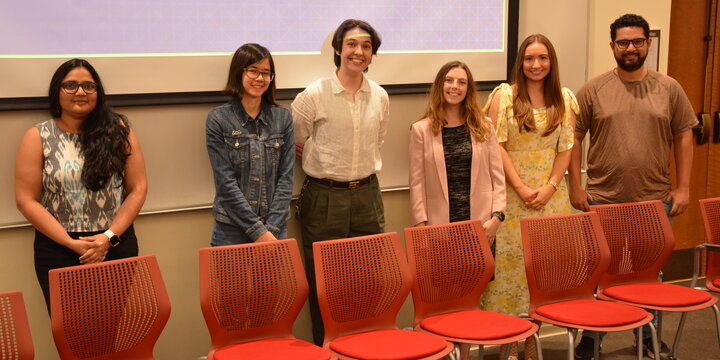 A group of students standing for a photo in front of a projector screen