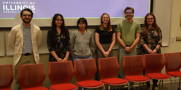 A photo of a group of students standing for a photo in front of a projector screen