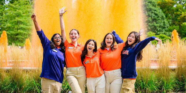 Several happy students in front of a fountain