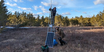 People setting up an antenna in a field