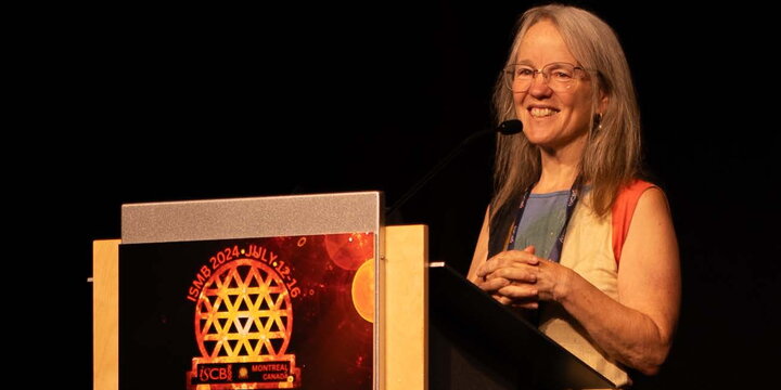 Tandy Warnow standing at a podium