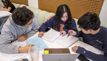 Students collaborating with notes around a laptop