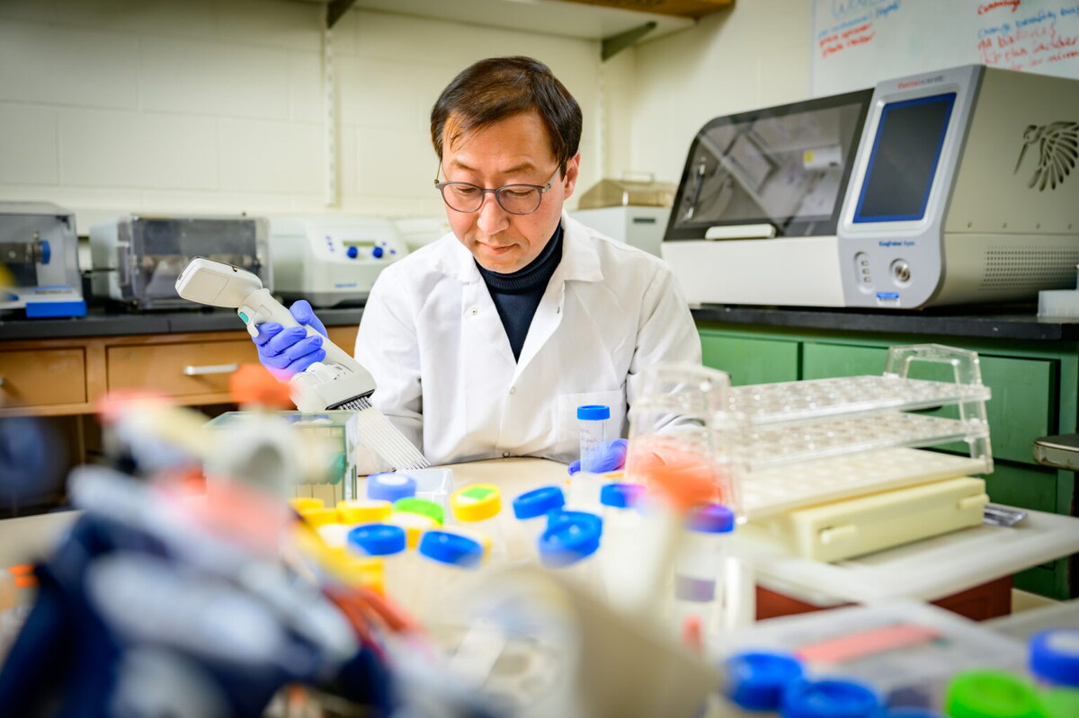 A man in glasses and a lab coat working with scientific instruments