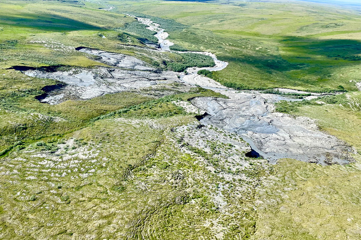 A wides shot of a green grassy area with a winding permafrost section