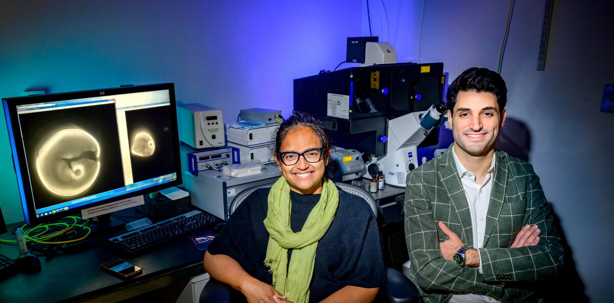 A man and a woman smiling and sitting near a computer
