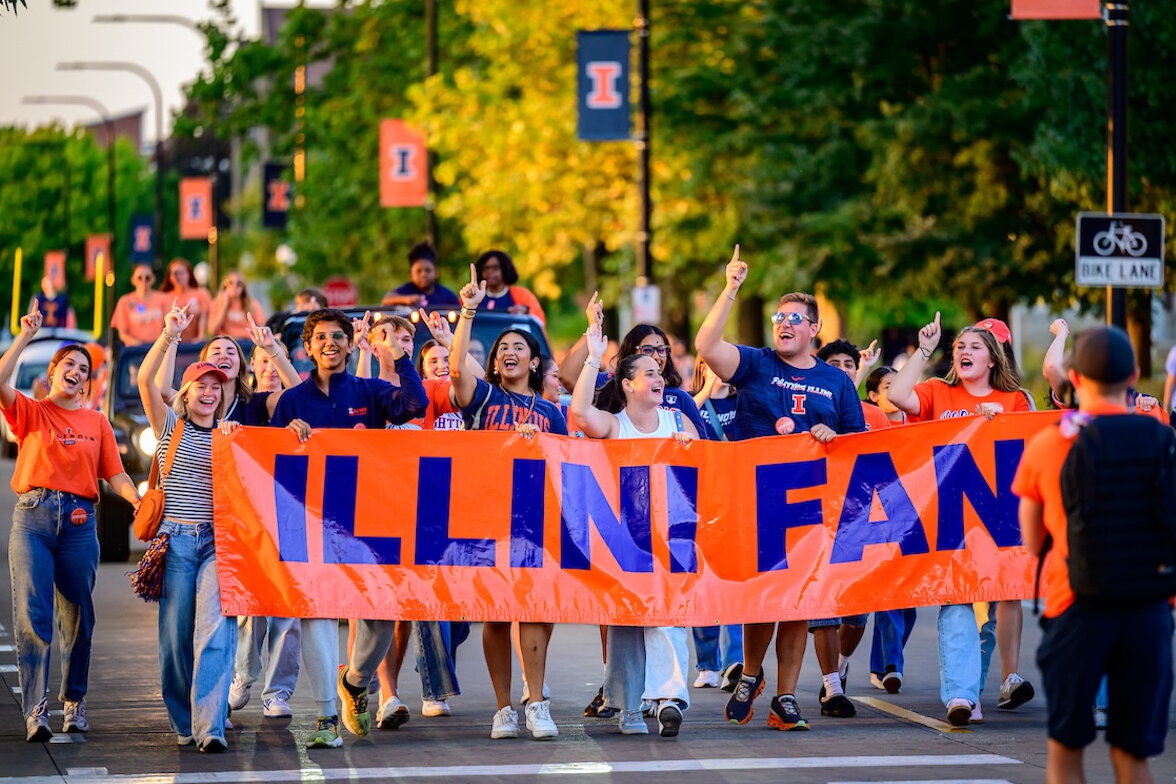 A group of people marching with a banner that says "Illini Fan"