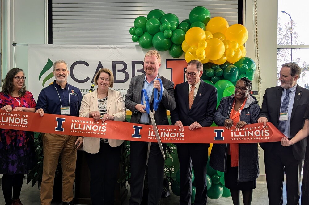 A group of individuals cutting a giant ribbon