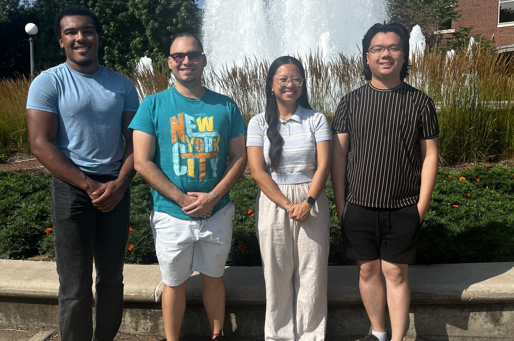 students posing next to one another in front of a fountain