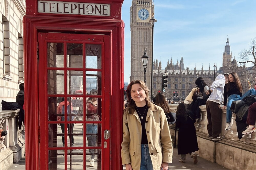 a woman standing next to a red telephone box