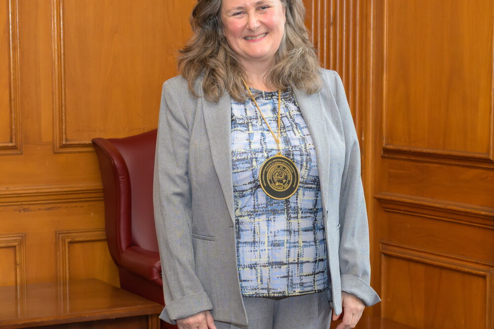 a smiling woman wearing a medallion