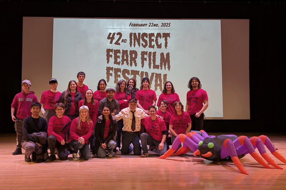 A group of people in red shirts standing in front of a projector and next to an inflatable spider