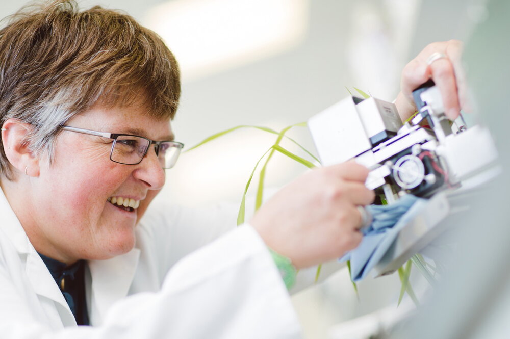 A smiling woman in a lab coat working with a piece of technology