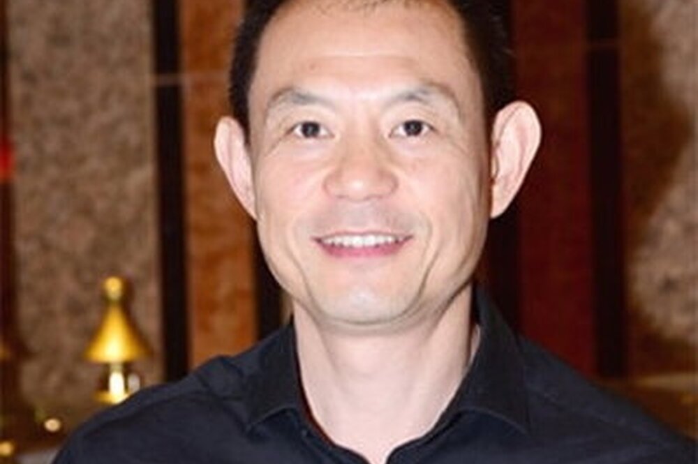 a man smiling in a blue button down shirt