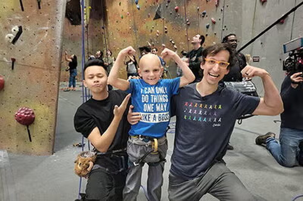 Two men flexing and smiling with a bald child in the middle also flexing