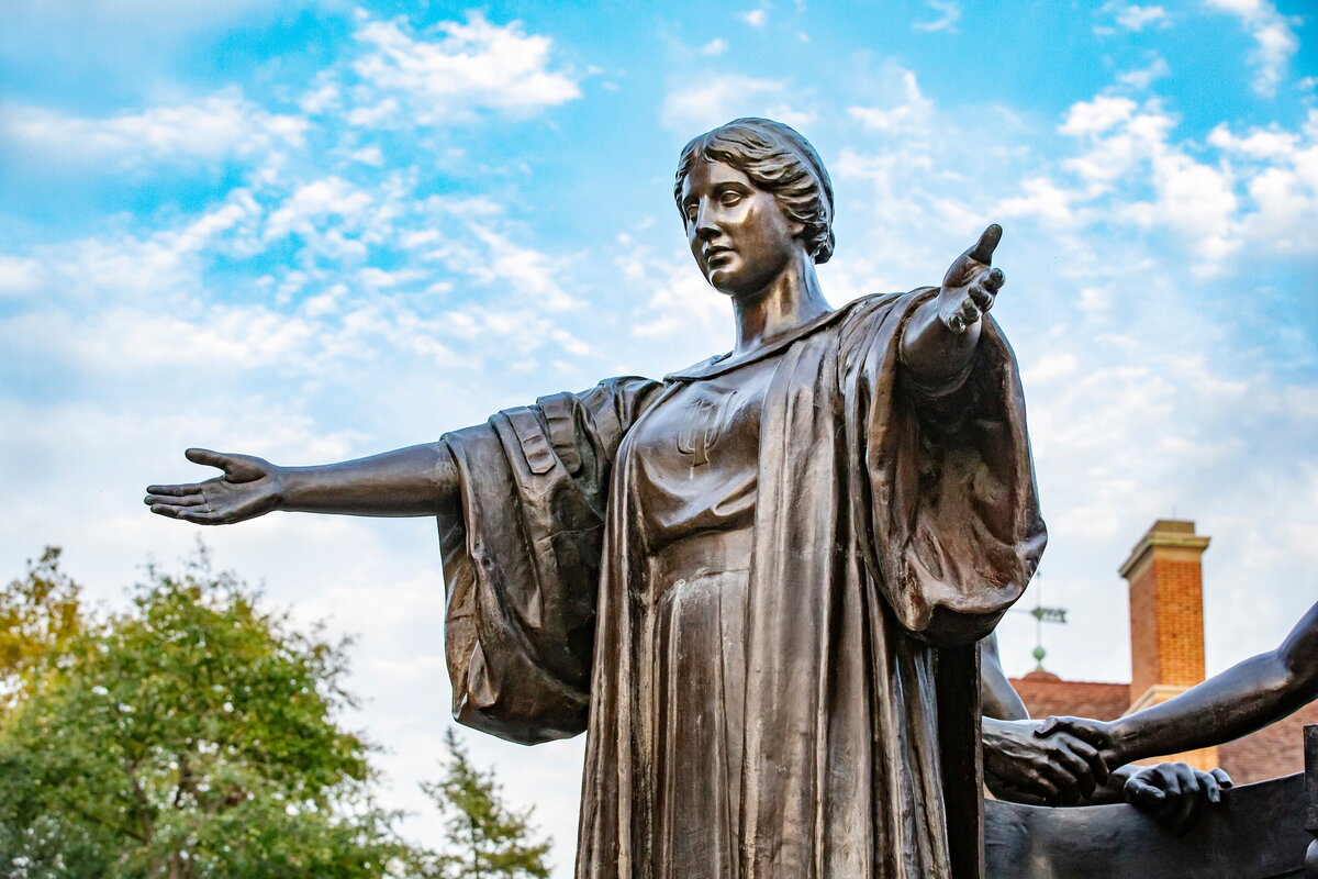 A statue with its arms open on a sunny day with blue sky and white clouds