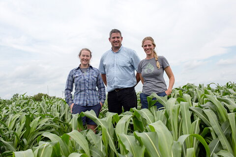 three smiling people in a field