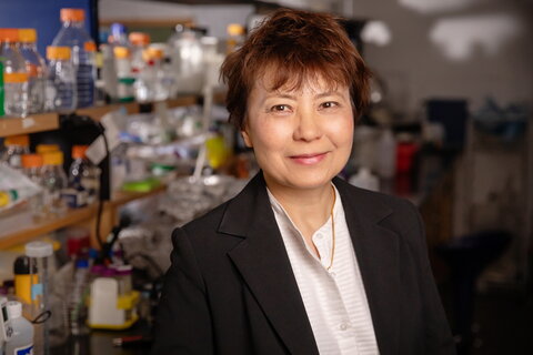 smiling person in front of a lab shelf