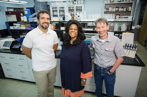 three smiling people in a lab