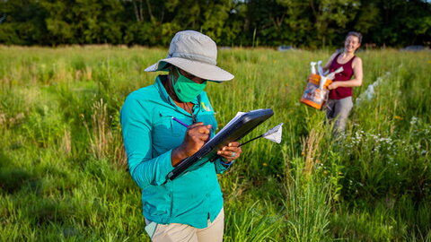 person writing on a clipboard in a field