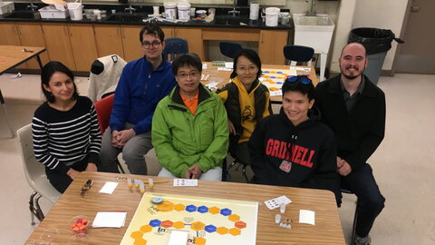 six people sitting in front of a board game