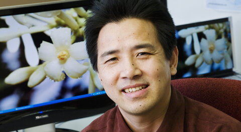 smiling man next to computer screen showing flowers