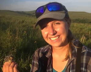 Sarah in sunny field holding bird