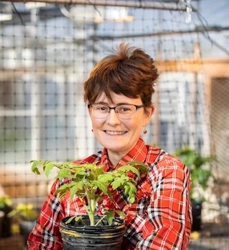 Erinn in greenhouse holding plant in pot