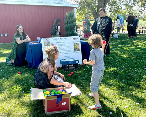 a young boy throwing a ball into a carton