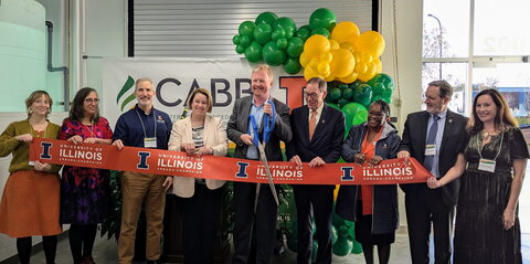 A group of individuals cutting a giant ribbon