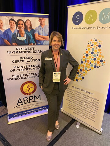 A photo of a person standing in front of two conference posters