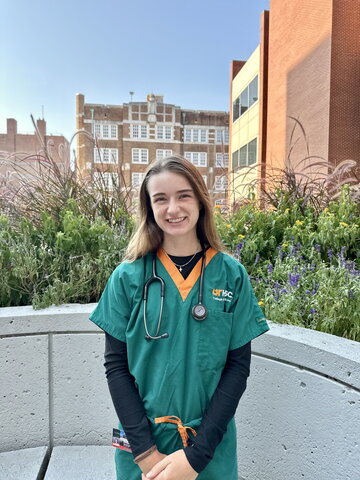 A photo of a young woman in green and orange scrubs