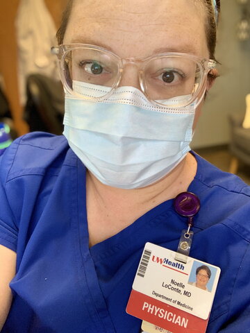 A photo of a person in glasses wearing a mask in scrubs