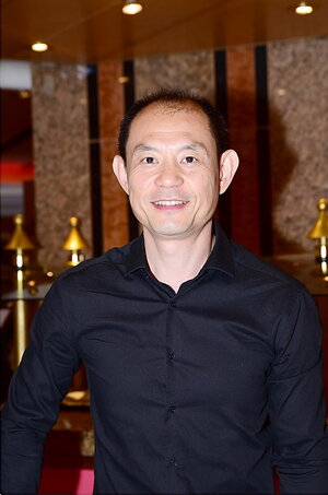 A photo of Joe Zhou in a building in a black button down shirt
