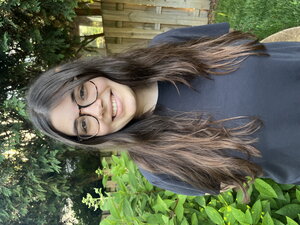 Rebecca standing in a backyard with a fence and bush behind them