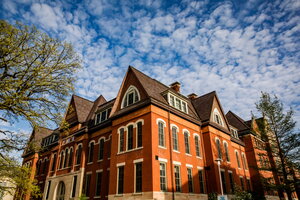 A photo of an old orange building with a brown roof that has white clouds and blue sky above it