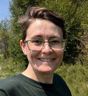 A photo of a woman in front of trees