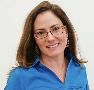 A smiling woman in glasses and a blue shirt
